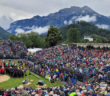 outdoor festival arena with seating stands and backdrop of mountains