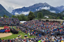 outdoor festival arena with seating stands and backdrop of mountains
