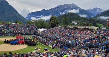 outdoor festival arena with seating stands and backdrop of mountains