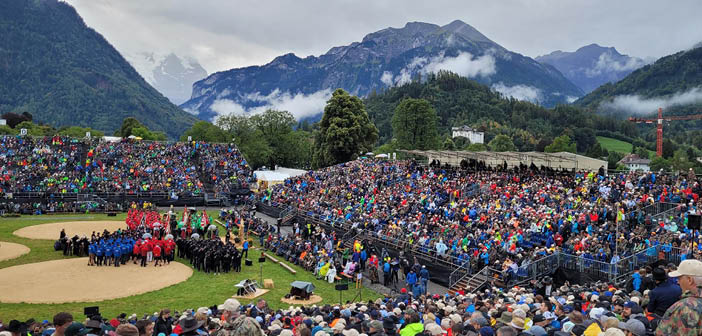 outdoor festival arena with seating stands and backdrop of mountains
